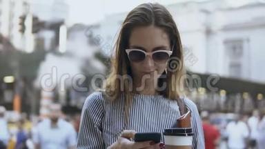 年轻漂亮<strong>的</strong>女商人站在<strong>拥挤的街道</strong>上，拿着咖啡和文件，用智能手机。