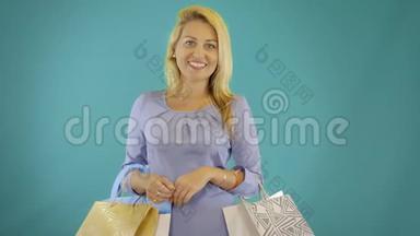 年轻女子带着购物袋<strong>走路</strong>，孤立在蓝色坚实的背景下。 前景。