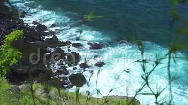 在绿色植物的背景下，<strong>海浪</strong>拍打到<strong>岩石</strong>海滩。 汹涌的<strong>海浪</strong>溅到石崖，泡沫和