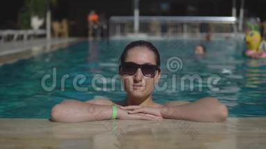 美丽的年轻女孩戴着太阳镜在室外游<strong>泳池</strong>游泳，在阳光明媚的<strong>夏日</strong>。