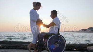 <strong>残疾人</strong>和妻子在晚上跳舞，残疾配偶在轮椅上，孕妇在<strong>日</strong>落时跳舞
