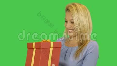 女孩得到红色礼盒。 年轻女子快乐金发带礼物。 阿尔法通道