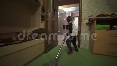 男孩拿着吸尘器打扫房间。 帮助父母处理家庭事务。