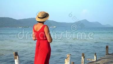 两个视频镜头。 穿着红色长裙的女人.. 这位穿红色衣服的年轻女子在码头上花钱，远远地看着。