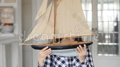 一位快乐的年轻女子手里拿着一艘帆船的模型