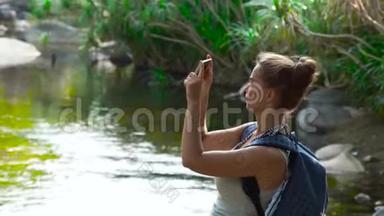 在丛林森林徒步旅行时，旅行妇女使用<strong>手机</strong>拍照。 女游客<strong>拍摄</strong>智能<strong>手机</strong>视频