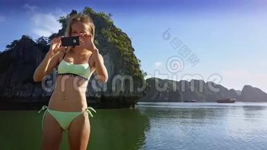 年轻女子在船上用Iphone和帆拍照