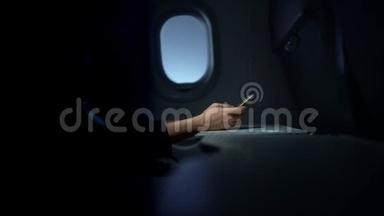 女人在黑暗的飞机上用手在智能手机上打字
