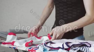女士在家洗衣服后用熨斗在熨衣板上熨烫衣服。