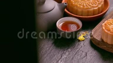 <strong>美</strong>丽的月饼在一个木盘上，茶和花在黑色背景上。 中国传统<strong>中秋节</strong>