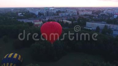 黎明时分，红热气球飘过城市绿地，节日早飞