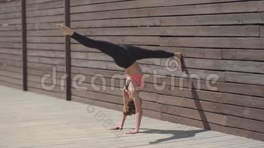在阳光明媚的日子里，女人在墙上练习瑜伽倒立姿势