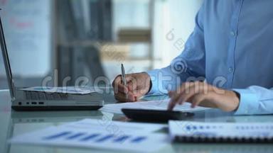 公司<strong>营销人员</strong>清点计算器和填写报告，坐在办公桌旁