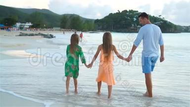 爸爸和孩子们享受海滩暑假热带假期。 一家人在海边散步。 流动人口