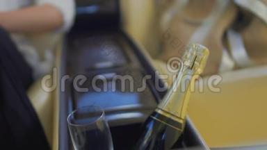 汽车储物箱内有<strong>香槟</strong>瓶和<strong>玻璃杯</strong>，坐在后座的女士