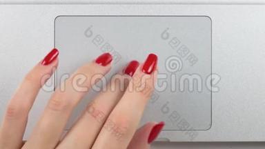 4K镜头。 女人的左手`红色指甲使用和点击一个轨迹板。 俯视图，特写