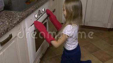 家庭厨房年轻女孩穿红色手套拿托盘与姜饼干从烤箱。 烤箱里的热饼干。 手工制作的餐餐