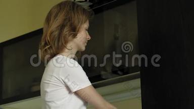 一个年轻的女人<strong>打开冰箱</strong>，选择产品。 上午