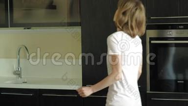 一个年轻的女人打开<strong>冰箱</strong>，选择产品。 上午