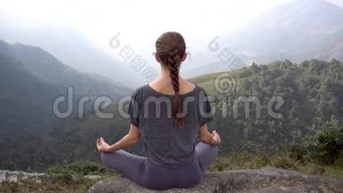 在越南萨帕的山崖上，瑜伽女人坐在冥想姿势帕达马萨纳