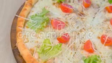 披萨，上面有鸡肉和奶酪，西红柿和生菜在木板上。