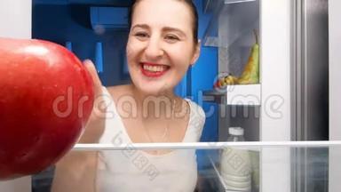 年轻微笑的女人<strong>打开冰箱</strong>咬红多汁苹果的4K镜头