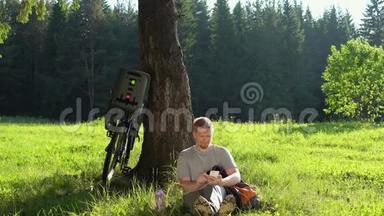 在阳光明媚的一天，男子<strong>游客</strong>骑着自行车在夏天的<strong>森林</strong>里休息。
