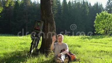 在阳光明媚的一天，男子游客骑着自行车在夏天的森林里休息。