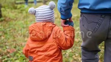 一位年轻的父亲和孩子一起在公园里散步。 父亲牵着儿子`手。 温柔和拥抱她心爱的父亲。