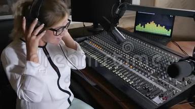 女人在广播室的大肚子上戴着耳机，有害的工作