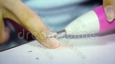 一个指甲丑陋的女孩用一台特殊的机器从指甲中去除指甲油，为修指甲做准备。 关闭