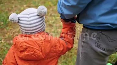 一位年轻的父亲和孩子一起在公园里散步。 父亲牵着儿子`手。 温柔和拥抱她心爱的父亲。