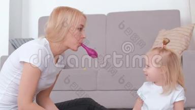 迷人的年轻金发妈妈为<strong>坐</strong>在沙发附近的迷人女儿充气<strong>气球</strong>。 家庭消遣。