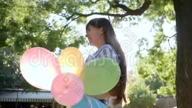 快乐的女孩带着五颜六色的气球跑来祝贺女朋友在公园过生日