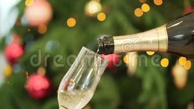 特写香槟<strong>倒入</strong>酒杯，背景上的圣诞树。 将香槟<strong>倒入</strong>玻璃的特写镜头