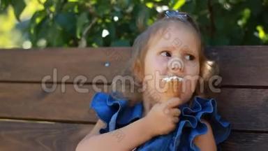 小女孩坐在公园的长凳上吃冰淇淋。