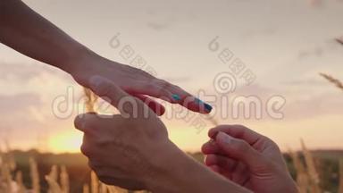 日落时分，一个男人正在给一个女人穿订婚戒指。 在镜框里只能看到手