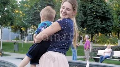 <strong>慢镜头视频</strong>快乐微笑的母亲拥抱和抱着她2岁的小男孩在公园