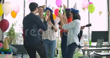 一群年轻人在他们的办公室里跳舞，玩得开心，用烤面包和叮叮当当的举杯庆祝。