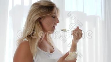 一个大肚子孕妇的特写镜头在背景窗上吃奶酪