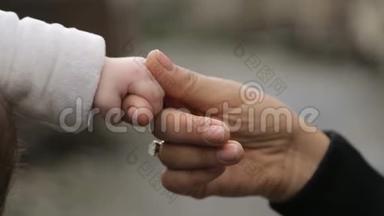 母亲握着婴儿的小手，带着温柔和关怀，带着母爱