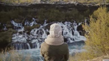 站在山谷中仰望冰岛瀑布，探索自然的年轻女子背影。