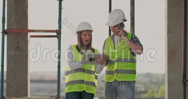 建筑在建筑中，有一个女的和一个男的建筑建筑工人，工程师沿着它走。