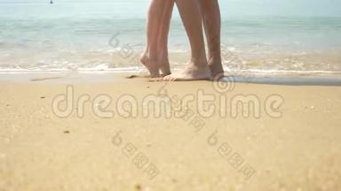 一对夫妇在晴朗的晴天沿着海滩散步。 他们牵手亲吻。 男人和女人<strong>走路</strong>的脚