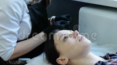 美容治疗。 美容师在女人的眼睛下面贴补丁。 侧视。