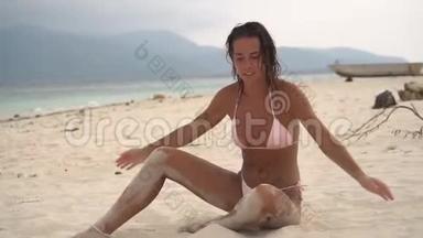 漂亮的年轻女子坐在白沙滩上，尽情享受夏天的假期，尽情地尽情享受