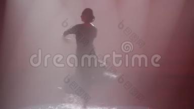 在探照灯的光束中在水中转动一个犯规。 舞蹈运动。 舞蹈演员在水中表演Contemp