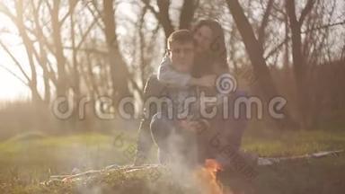 一个年轻的<strong>女孩</strong>在火边拥抱她的男朋友。 那个男人和那个<strong>女孩</strong>欣<strong>赏</strong>火焰