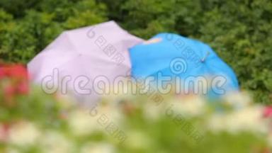 可爱的情侣坐在公园的长凳上，撑着五颜六色的雨伞，雨天