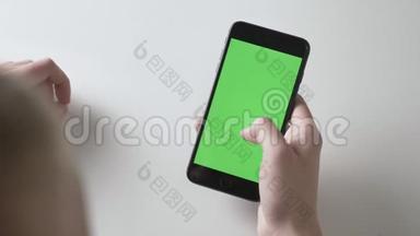 男人`<strong>双手握</strong>着一个黑色的大智能手机，挥动着手势。 绿色屏幕，色度概念60fps